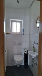 Helle Gästetoilette mit Fenster und Waschbecken in der Ferienwohnung.
