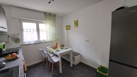 Moderne Küche mit Esstisch, hellen Möbeln und gedecktem Frühstückstisch in der Ferienwohnung.